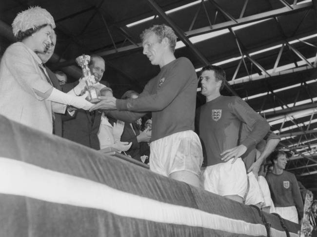 alx_elisabeth-personalidade-bobby-moore-capitao-inglaterra-futebol-copa-do-mundo-1966_original.jpeg O capitão da seleção inglesa, Bobby Moore, entrega taça para a rainha Elisabeth II, logo após a Inglaterra ganhar sua primeira Copa do Mundo - 30/07/1966