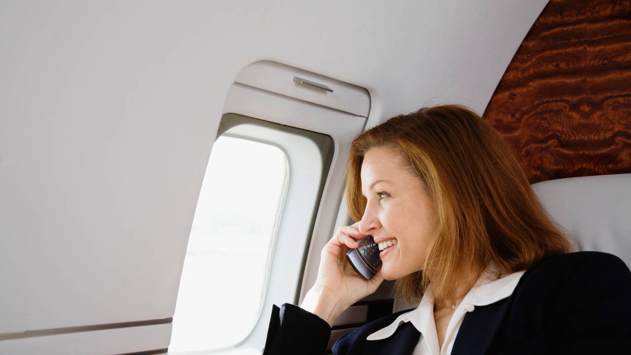 Mulher falando no celular dentro do avião