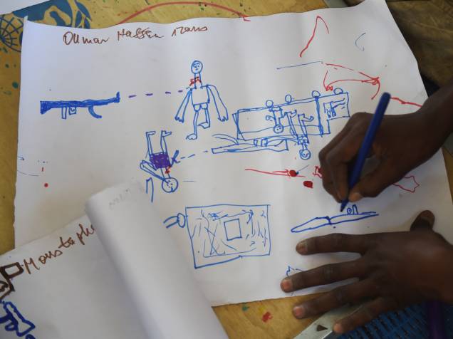 Jovens refugiados desenham cenas de ataque durante programa de terapia da UNICEF, próximo a Baga Sola Jovens refugiados desenham cenas de ataque durante programa de terapia da UNICEF, próximo a Baga Sola