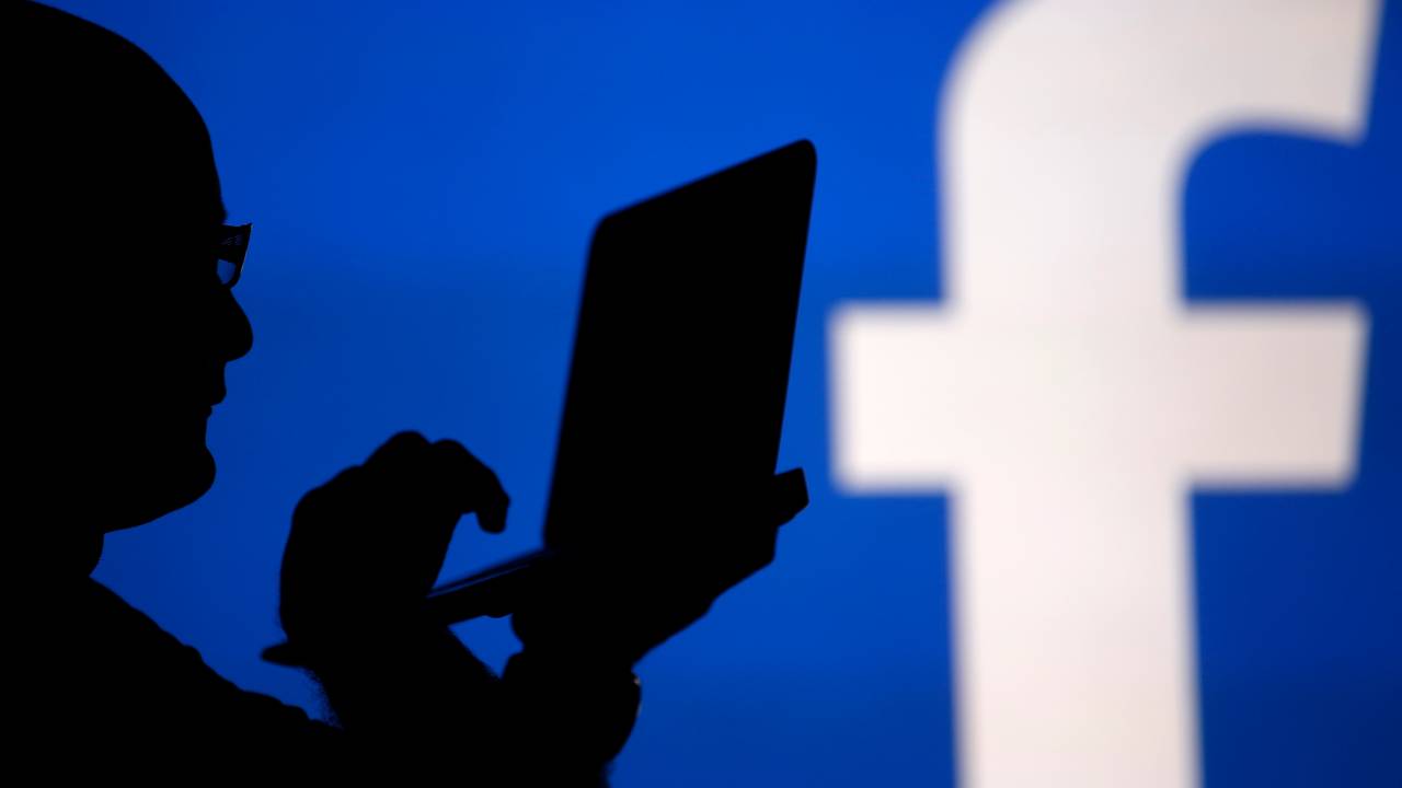 Homens em frente a um logo do Facebook