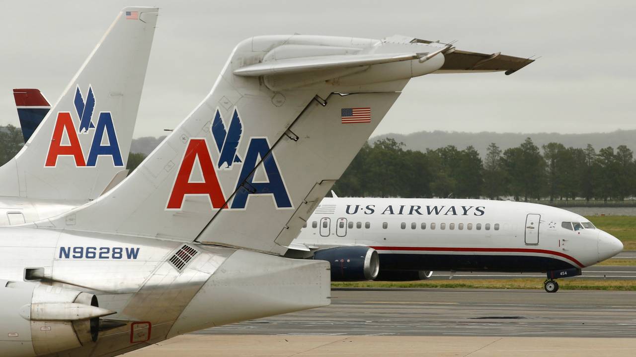 A US Airways plane and an American Airlines plane pass each other at Ronald Reagan National Airport in Arlington County, Virginia, in this file photo taken April 23, 2012. The unsecured creditors committee of bankrupt American Airlines parent AMR Corp has approved an $11 billion merger agreement with US Airways Group Inc, people familiar with the matter said on Wednesday. REUTERS/Kevin Lamarque/Files (UNITED STATES - Tags: TRANSPORT BUSINESS)