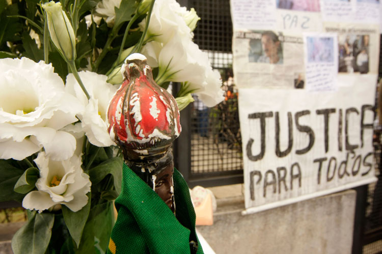 Manifestantes exibem cartazes pedindo justiça.