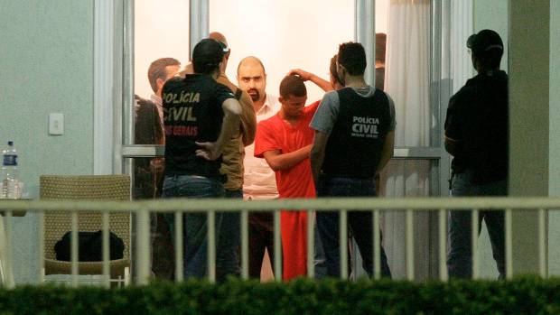 Primo do goleiro Bruno, S&eacute;rgio Rosa Sales, com uniforme laranja, orienta policiais durante a per&iacute;cia feita na &uacute;ltima noite, no s&iacute;tio do jogador em Esmeraldas.