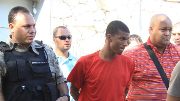 S&eacute;rgio Rosa Sales, de uniforme vermelho, &eacute; conduzido por policiais: primo do jogador Bruno mudou vers&atilde;o de depoimento e, agora, diz que o goleiro n&atilde;o foi ao local da execu&ccedil;&atilde;o de Eliza Samudio.<br>