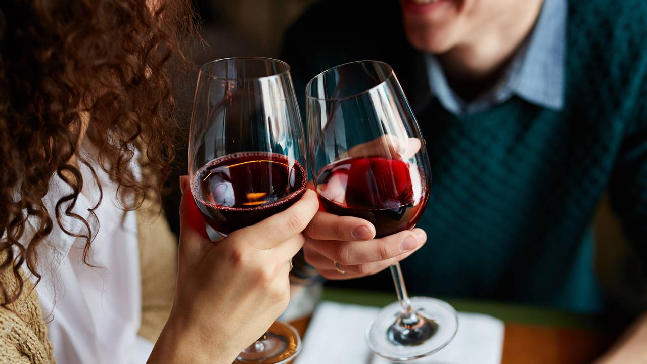 Casal brindando com vinho, em restaurante