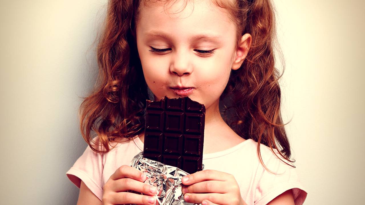 Menina criança comendo barra de chocolate