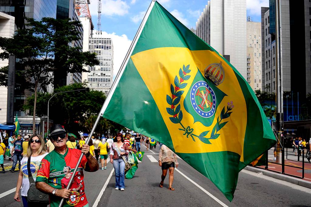 Na Avenida Paulista, um manifestante levanta a bandeira da monarquia durante o protesto organizado pelos movimentos sociais MBL (Movimento Brasil Livre) e "Vem Pra Rua", que tamb&eacute;m aconteceu em outras cidades do Brasil