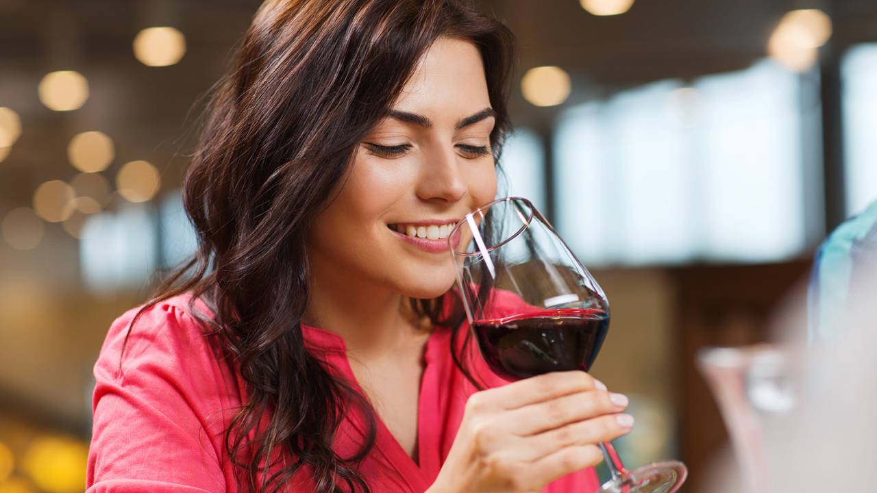Mulher bebe vinho sorrindo