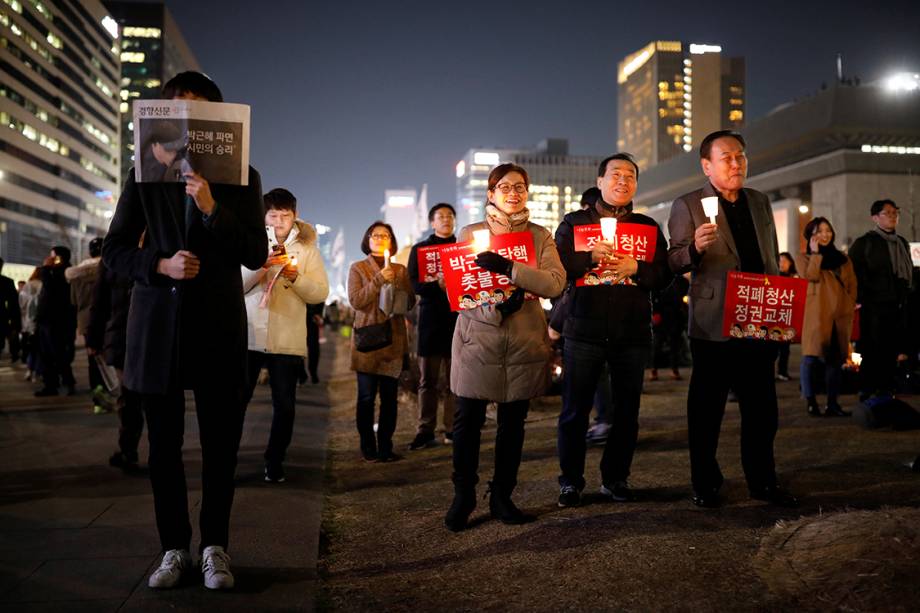 Manifestantes protestam contra a presidente Park Geun-hye, na Coreia do Sul, com cartazes que dizem "Cortemos o mal pela raiz, mudemos o regime" Manifestantes protestam contra a presidente Park Geun-hye, na Coreia do Sul, com cartazes que dizem "Cortemos o mal pela raiz, mudemos o regime"