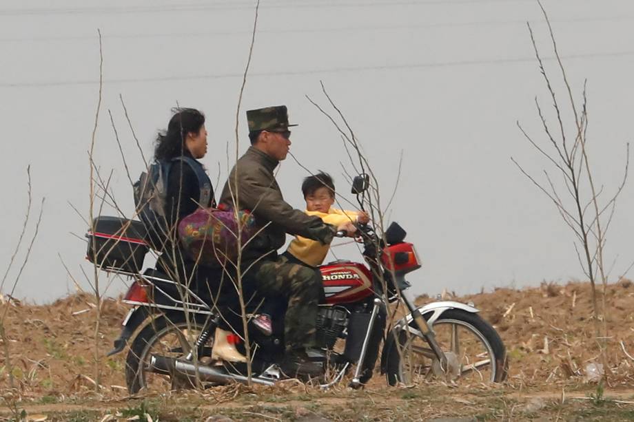 Soldado norte-coreano anda de moto com a família na fronteira com a China pelo rio Yalu, próximo a cidade de Sinuiju, na Coreia do Norte, e da província de Dandong, China  - 15/04/2017