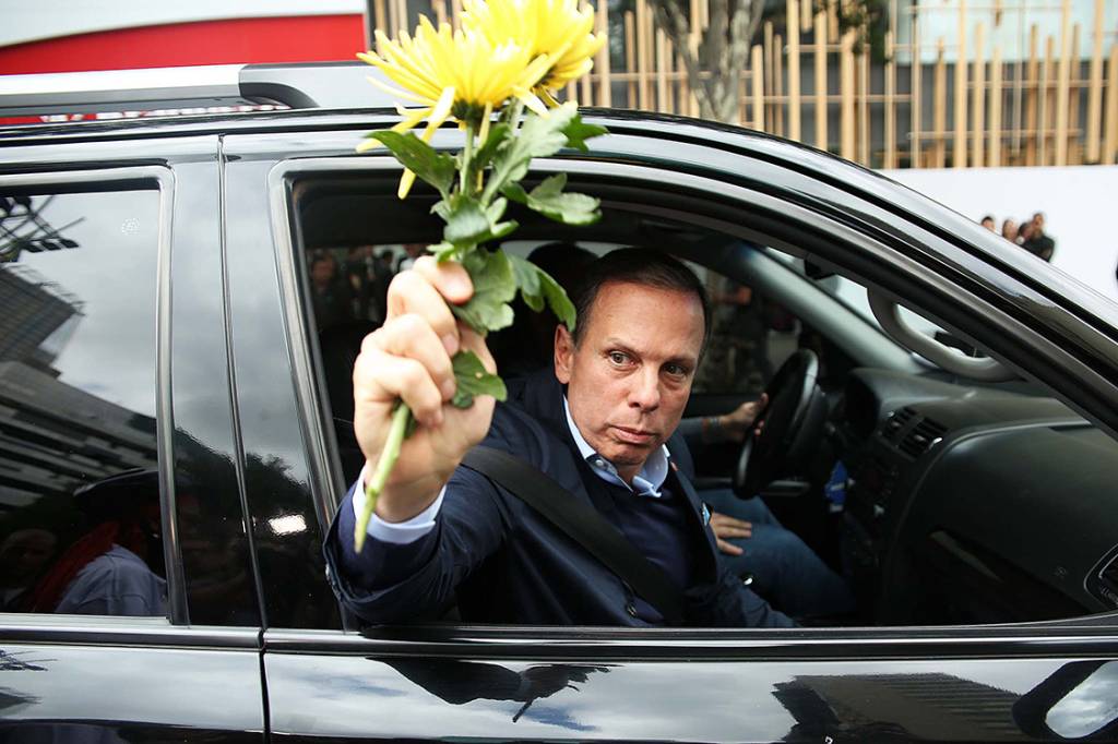 O prefeito João Dória recebe flores ciclista e joga fora