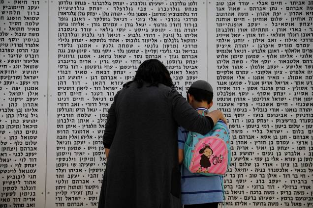 Uma mulher e um menino olham para um memorial em homenagem aos soldados mortos, em Israel Uma mulher e um menino olham para um memorial em homenagem aos soldados mortos, em Israel