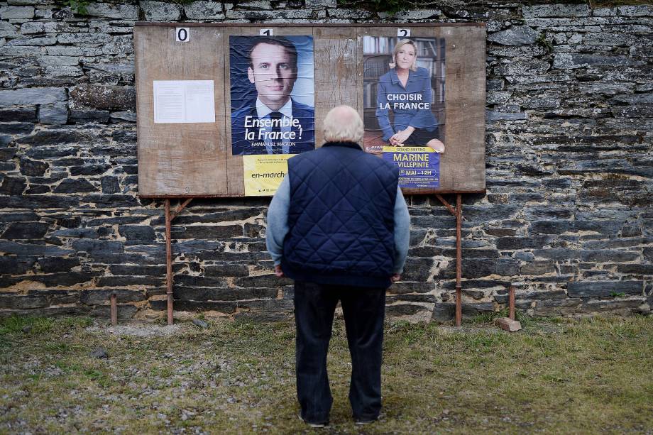 Homem observa cartazes dos candidatos perto de um local de votação durante o segundo turno das eleições presidenciais francesas na cidade rural de Saint-Sulpice-des-Landes - 07/05/2017