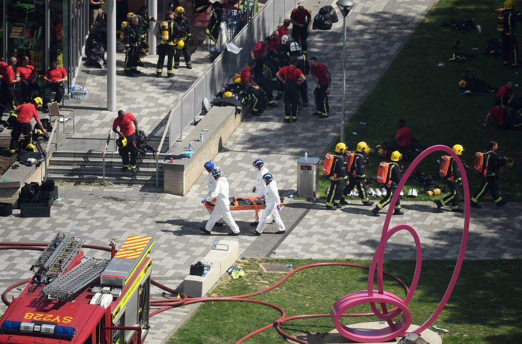Equipe de emergencia do corpo de bombeiros, policiais e demais ajudantes ao lado do local do inc&ecirc;ndio no Grenfell Tower, em Londres - 14/06/2017