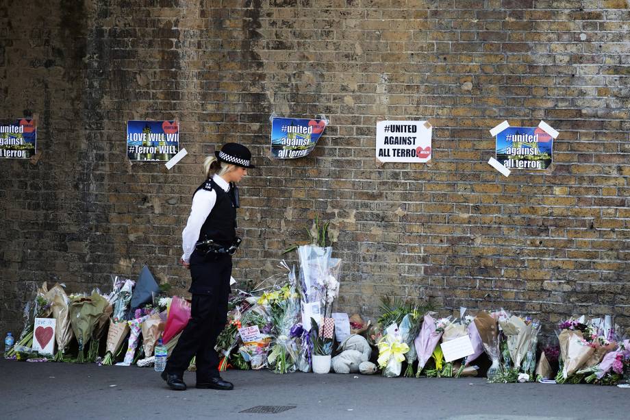 Uma policial vigia local onde pessoas deixam flores à vítima de atropelamento em Finsbury Park - 19/06/2017