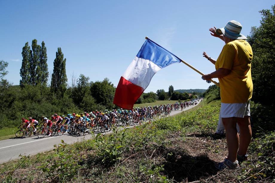 Torcedor segura bandeira da França enquanto o pelotão participa da etapa 6 de 216 km de Vesoul para Troyes, do Le Tour de France - 6 de julho de 2017