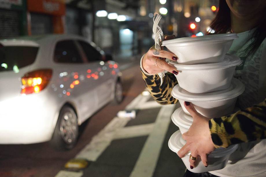 Voluntária carrega marmitas para distribuir para moradores de rua, na região central de São Paulo