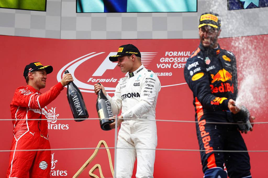 O finland&ecirc;s Valtteri Bottas, da Mercedes, comemora no p&oacute;dio com Sebastian Vettel, da Ferrari, e Daniel Ricciardo, da Red Bull Racing, ap&oacute;s vencer o GP da &Aacute;ustria