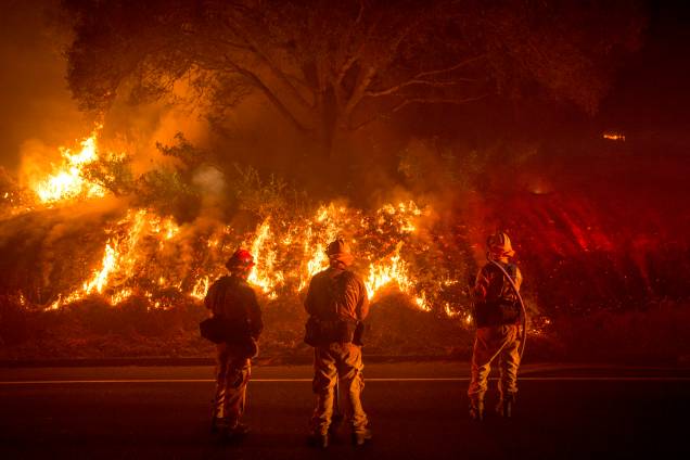 Três homens do corpo de bombeiros da Califórnia lutam contra as chamas do incêndio Detwiler que atingiu a pequena cidade de Mariposa e obrigou centenas de moradores a deixarem suas casas Três homens do corpo de bombeiros da Califórnia lutam contra as chamas do incêndio Detwiler que atingiu a pequena cidade de Mariposa e obrigou centenas de moradores a deixarem suas casas