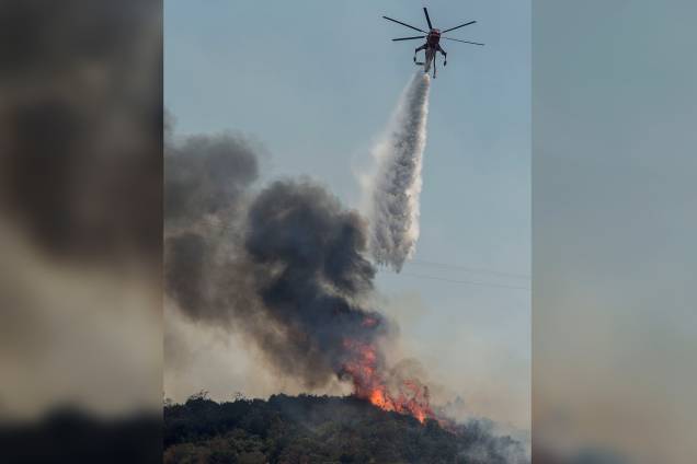 Um helicóptero do corpo de bombeiros despeja água para conter as chamas perto do Forte de Fremont, na estrada 49, depois que as autoridades pediram a evacuação do local devido ao fogo de Detwiler, em Mariposa, Califórnia Um helicóptero do corpo de bombeiros despeja água para conter as chamas perto do Forte de Fremont, na estrada 49, depois que as autoridades pediram a evacuação do local devido ao fogo de Detwiler, em Mariposa, Califórnia