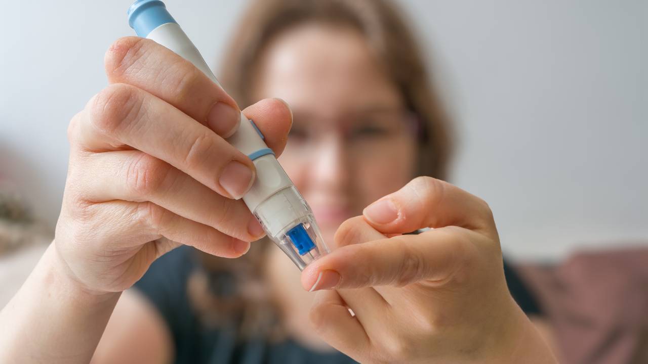 Mulher usando um aparelho para medir a taxa de glicose no sangue