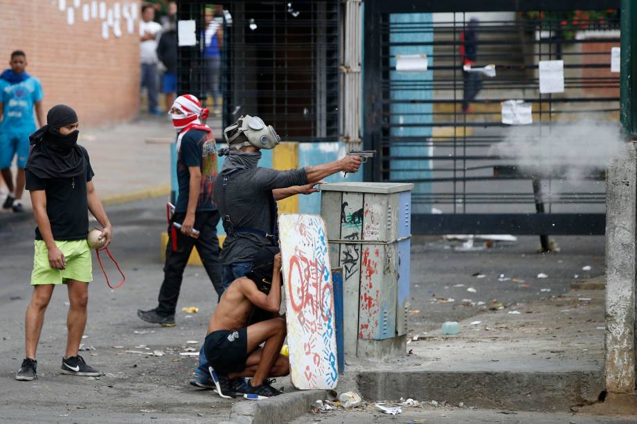 Manifestante dispara uma arma de fogo durante os confrontos com  forças governamentais enquanto se realizam as eleições da Assembleia Constituinte em Caracas, na Venezuela - 30/07/2017