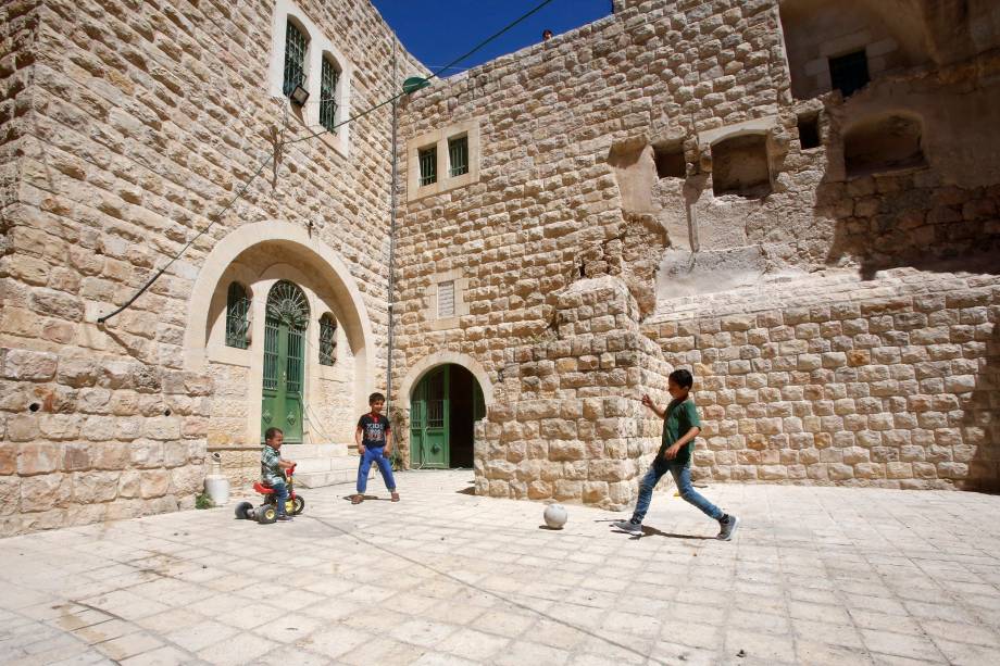 Crianças palestinas brincam com uma bola do lado de fora de sua casa na cidade velha de Hebron, na Cisjordânia