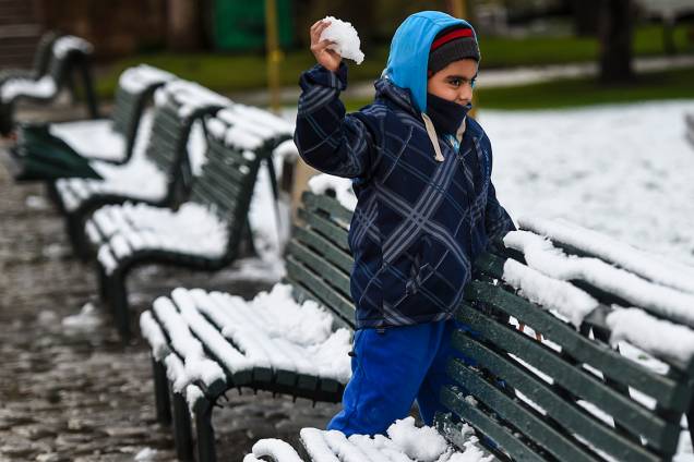 Criança atira bola de neve enquanto brinca em uma praça no centro de Santiago, após uma nevasca inesperada atingir a cidade, no Chile - 15/07/2017 Criança atira bola de neve enquanto brinca em uma praça no centro de Santiago, após uma nevasca inesperada atingir a cidade, no Chile - 15/07/2017