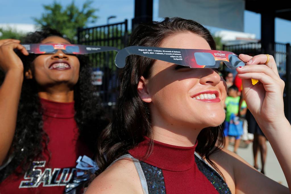 Animadoras de torcida usam &oacute;culos de vis&atilde;o solar antes de receber o p&uacute;blico em um est&aacute;dio de futebol-americano para assistir o eclipse solar total na Southern Illinois University em Carbondale, nos Estados Unidos - 21/08/2017