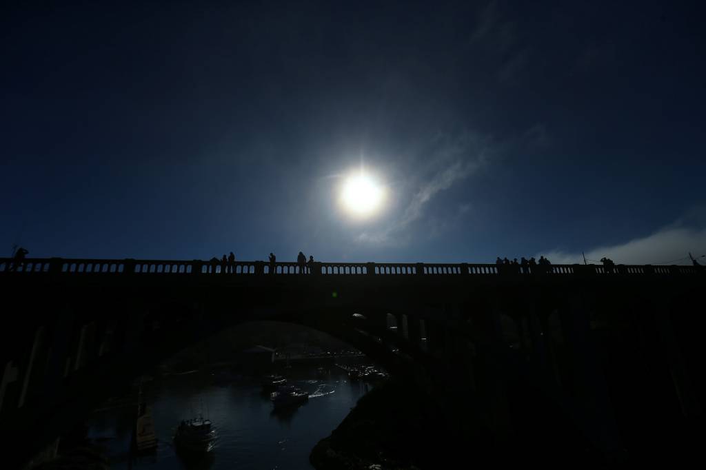 Pessoas se re&uacute;nem em uma ponte para acompanhar o eclipse solar em Depoe Bay, no estado americano do Oregon - 21/08/2017