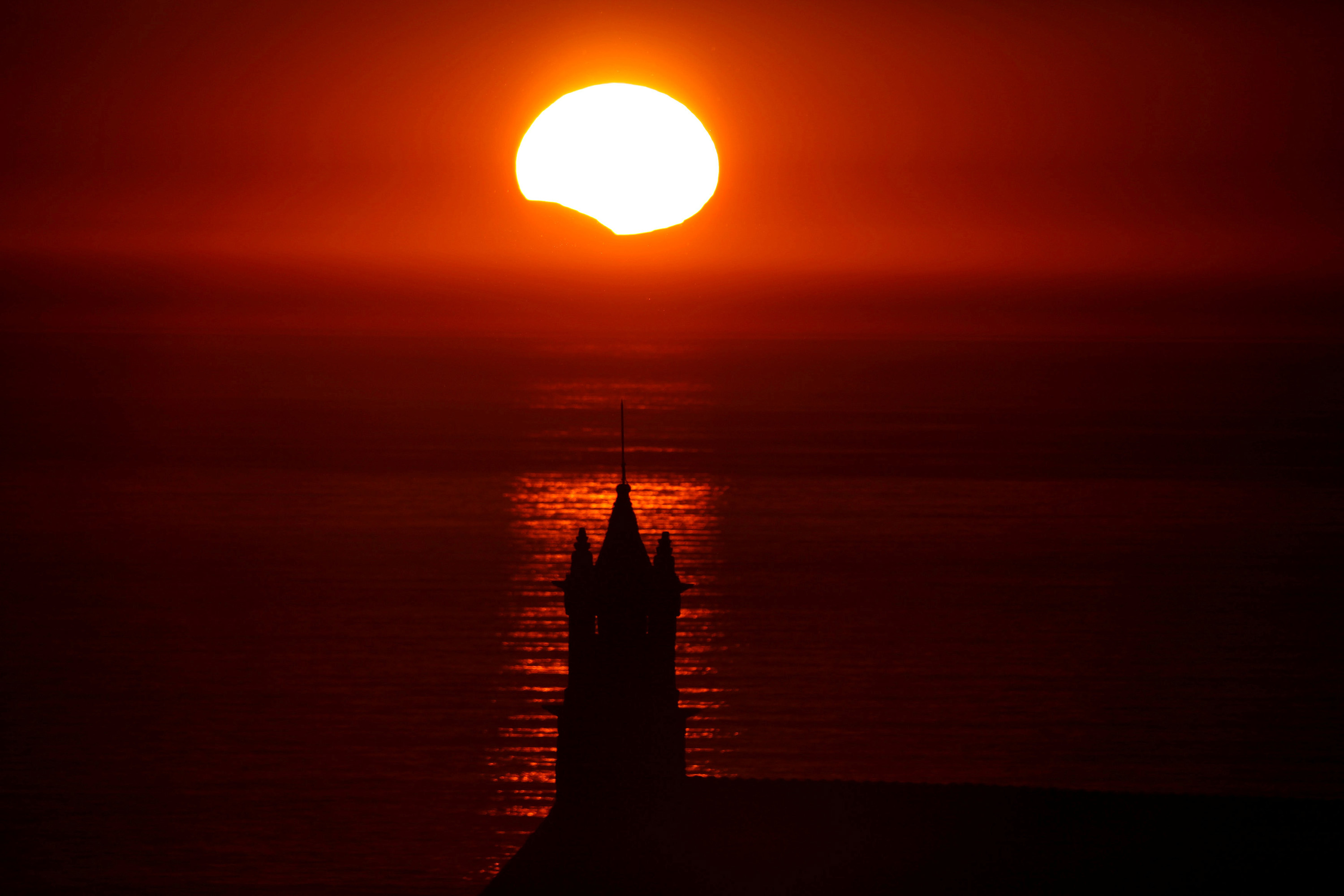 A Capela Saint-They &eacute; vista em silhueta ao p&ocirc;r-do-sol durante um eclipse solar parcial, na Bretanha, Fran&ccedil;a - 21/08/2017