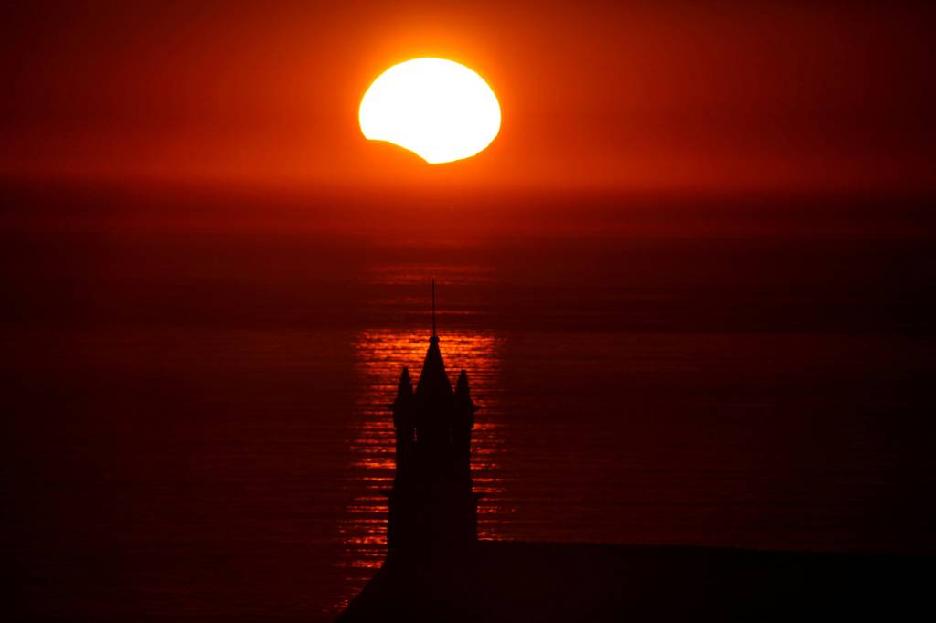 A Capela Saint-They &eacute; vista em silhueta ao p&ocirc;r-do-sol durante um eclipse solar parcial, na Bretanha, Fran&ccedil;a - 21/08/2017