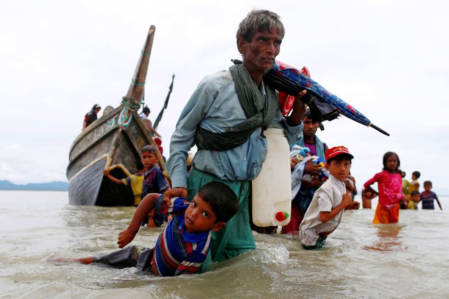 Refugiado rohingya carrega uma criança  até a costa após atravessar a fronteira entre Bangladesh e Myanmar de barco pela Baía de Bengala em Shah Porir Dwip, Bangladesh - 10/09/2017