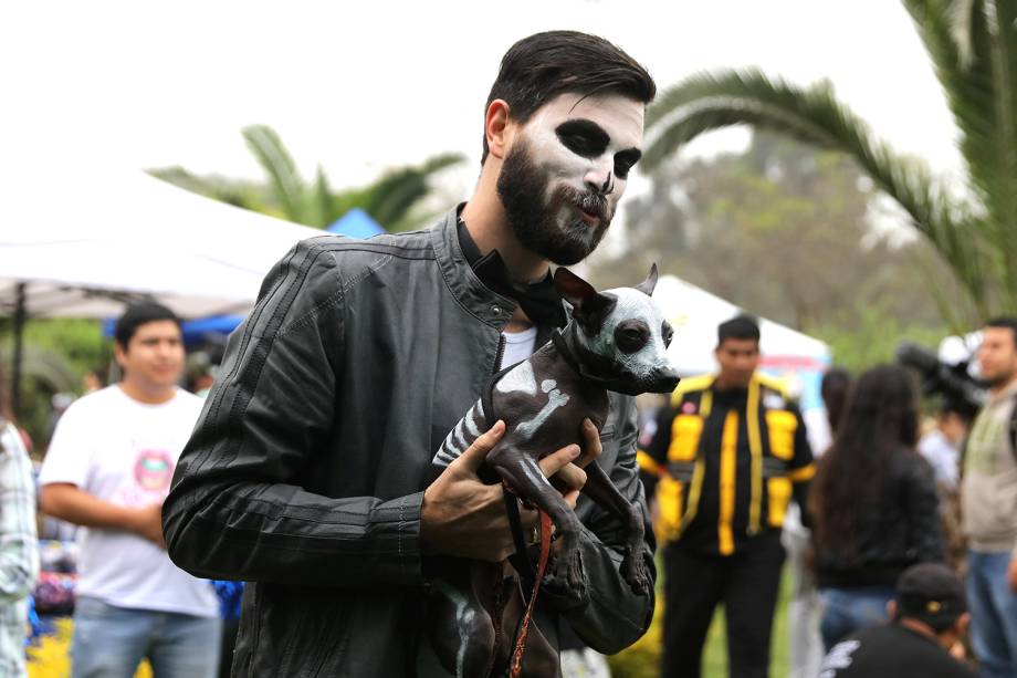 Homem segura cão durante desfile de Halloween para animais, em Lima, capital do Peru - 29/10/2017