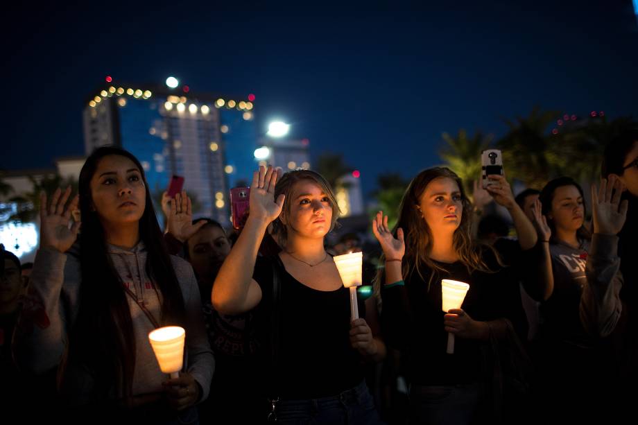 Pessoas se encontram no cruzamento da Avenida Sahara com a Las Vegas Boulevard, e levantam a mão direita clamando por um mundo mais pacífico durante homenagem às vitimas do tiroteio no festival de música country 'Route 91 Harvest' em Las Vegas - 02/10/2017