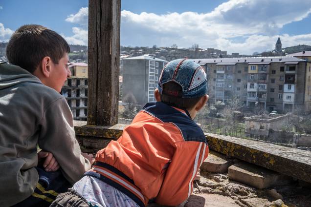 Crianças observam prédios destruídos pela guerra em Artsakh. Crianças observam prédios destruídos pela guerra em Artsakh.