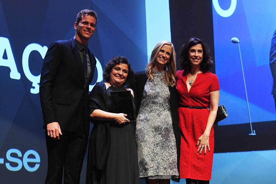 Flávia Rezek, vencedora do Prêmio Veja-se na categoria 'Educação', recebe o prêmio ao lado da mestre de cerimônias do evento, a atriz Fernanda Torres, e dos responsáveis por entregar o troféu na categoria, a professora Claudia Costin e o nadador Cesar Cielo