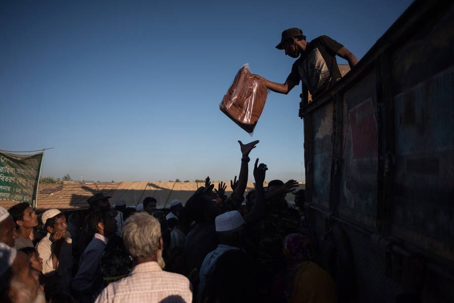 Homem auxilia na distribuição de cobertores para os refugiados roghingya do acampamento de Cox's Bazar, no Bangladesh - 05/12/2017