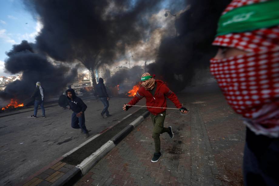 Manifestantes palestinos correm durante confrontos com tropas israelenses em um protesto contra a decisão do presidente dos Estados Unidos, Donald Trump, de reconhecer Jerusalém como a capital de Israel, perto do assentamento judeu de Beit El, nos arredores da cidade de Ramallah, na Cisjordânia - 07/12/2017