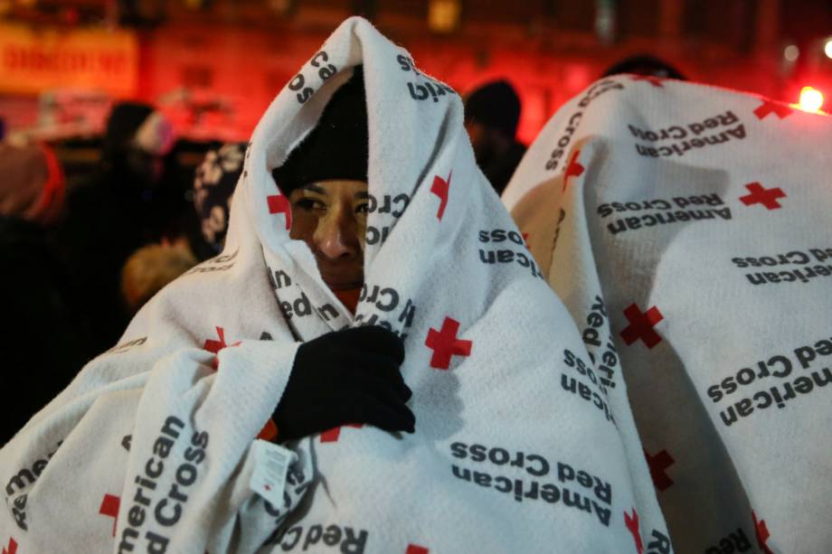 Moradores usam cobertores após serem retirados de um edifício em chamas no bairro do Bronx, em Nova York - 28/12/2017