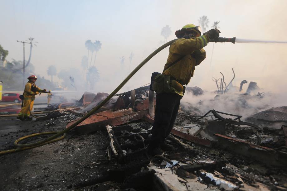 Bombeiros pulverizam água nos restos de um complexo de apartamentos destruído pelo Thomas Fire em Ventura, na Califórnia - 05/12/2017