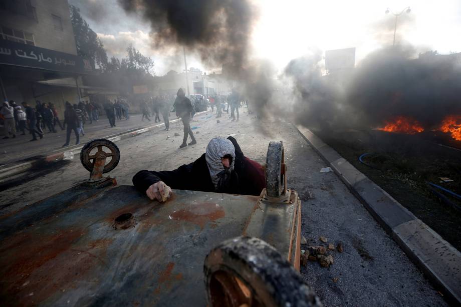 Manifestante palestino se protege atrás de uma caçamba durante confronto com as tropas israelenses em protesto contra a decisão do presidente dos Estados Unidos, Donald Trump, de reconhecer Jerusalém como a capital de Israel - 07/12/2017