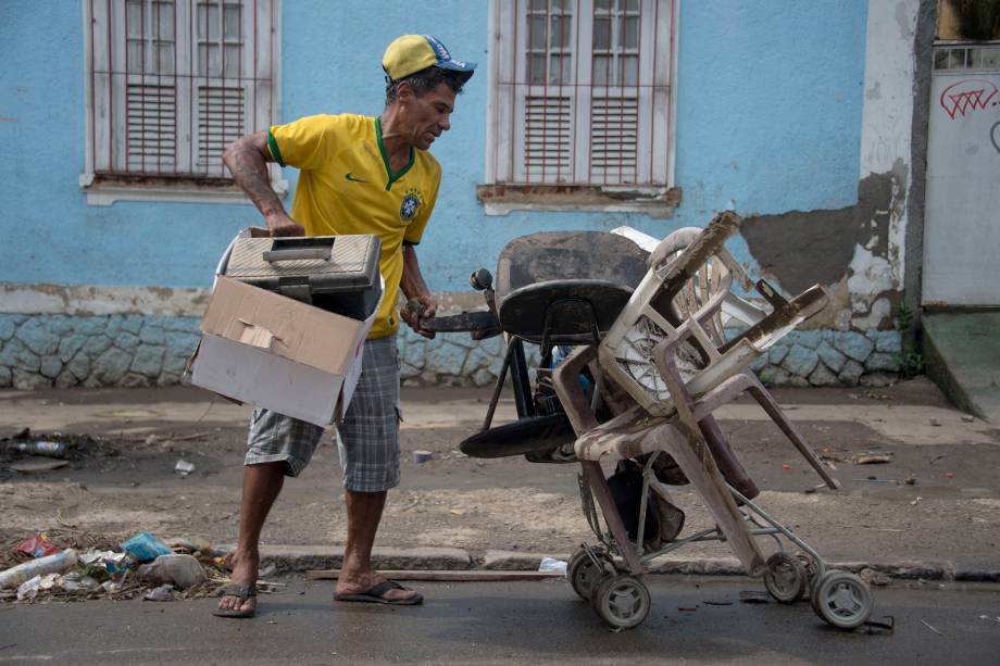 Homem tenta recuperar seus pertences após enchente provocada pelas fortes chuvas em Bonsucesso, no Rio de Janeiro - 15/02/2018