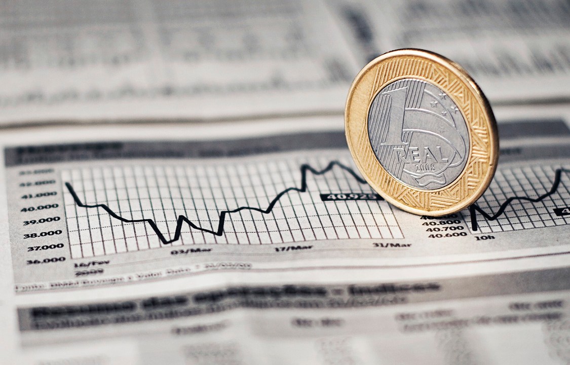 Brazilian Economy Real, economia brasileira, with a 1 Real coin over a graphic in a newspaper. Jornal com moeda em cima do grA!fico.