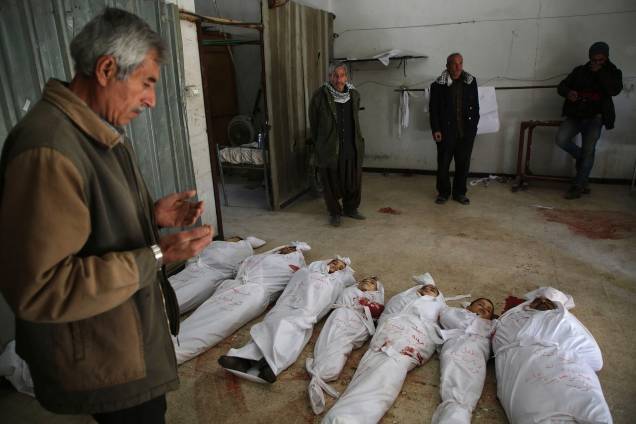 Homem faz orações ao lado de corpos preparados para o o funeral de vítimas civis mortas durante ataques aéreos do governo na cidade rebelde de Arbin, na região sitiada de Ghouta Oriental - 20/02/2018 Homem faz orações ao lado de corpos preparados para o o funeral de vítimas civis mortas durante ataques aéreos do governo na cidade rebelde de Arbin, na região sitiada de Ghouta Oriental - 20/02/2018