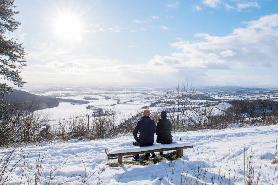 Casal é fotografado sentado em um banco, durante onda de frio no Sutton Bank National Park Centre, localizado no Reino Unido - 27/02/2018