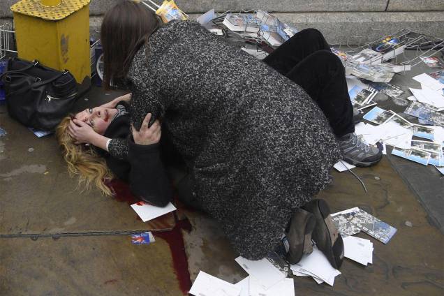 Mulher é vista ajudando uma vítima ferida no chão depois que Khalid Masood dirigiu seu carro na direção de pedestres matando quatro, além de um policial na Westminster Bridge em Londres, Grã-Bretanha - 22/03/2017 Mulher é vista ajudando uma vítima ferida no chão depois que Khalid Masood dirigiu seu carro na direção de pedestres matando quatro, além de um policial na Westminster Bridge em Londres, Grã-Bretanha - 22/03/2017