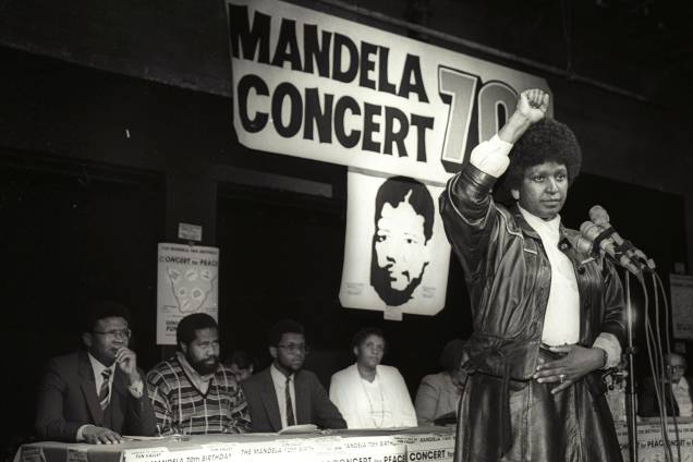 Winnie Mandela levanta a mão em uma saudação ao poder negro após anunciar que um enorme show pop será realizado para marcar o 70º aniversário de seu marido, o líder nacionalista negro encarcerado Nelson Mandela - 17/07/1988 Winnie Mandela levanta a mão em uma saudação ao poder negro após anunciar que um enorme show pop será realizado para marcar o 70º aniversário de seu marido, o líder nacionalista negro encarcerado Nelson Mandela - 17/07/1988