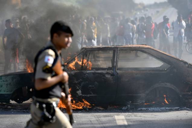 Policial passa por um carro incendiado por manifestantes que protestam contra os preços dos combustíveis no bairro de São Marino, em Ribeirão das Neves, região metropolitana de Belo Horizonte (MG) - 25/05/2018 Policial passa por um carro incendiado por manifestantes que protestam contra os preços dos combustíveis no bairro de São Marino, em Ribeirão das Neves, região metropolitana de Belo Horizonte (MG) - 25/05/2018