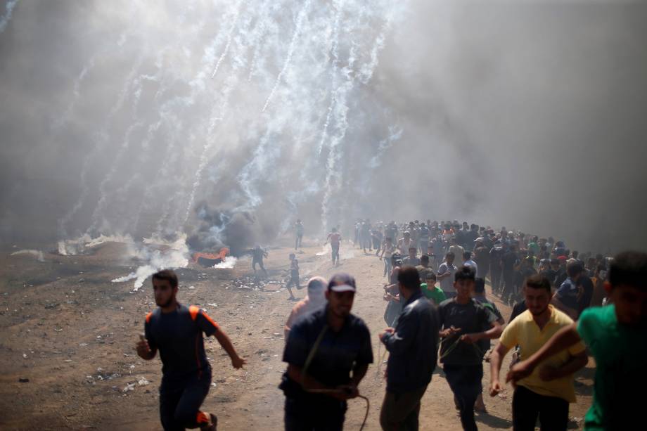 Manifestantes Palestinos fogem de bombas de gás lacrimogênio na Faixa de Gaza - 14/05/2018 Manifestantes Palestinos fogem de bombas de gás lacrimogênio na Faixa de Gaza - 14/05/2018